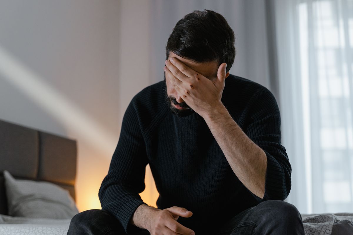 Man alone on the edge of the bed at night
